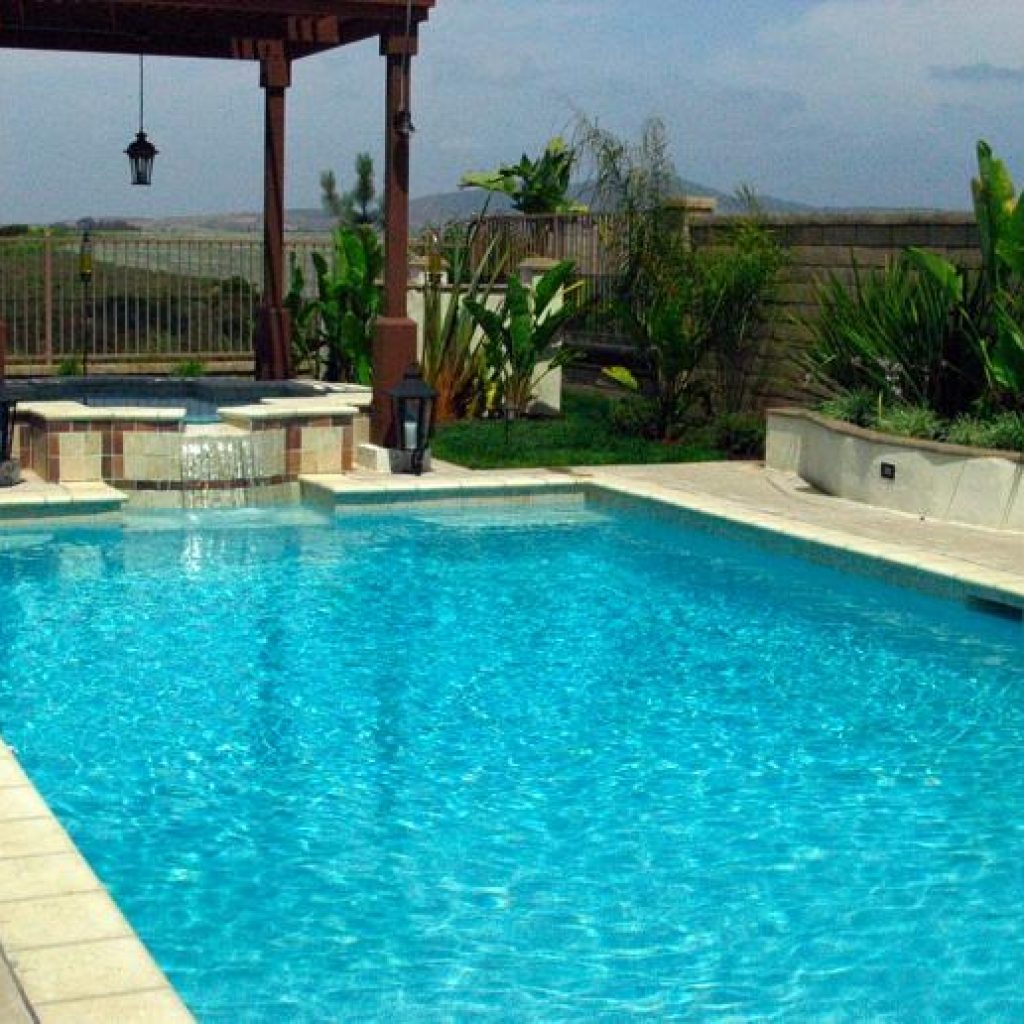 A geometric pool with spa underneath a gazebo.